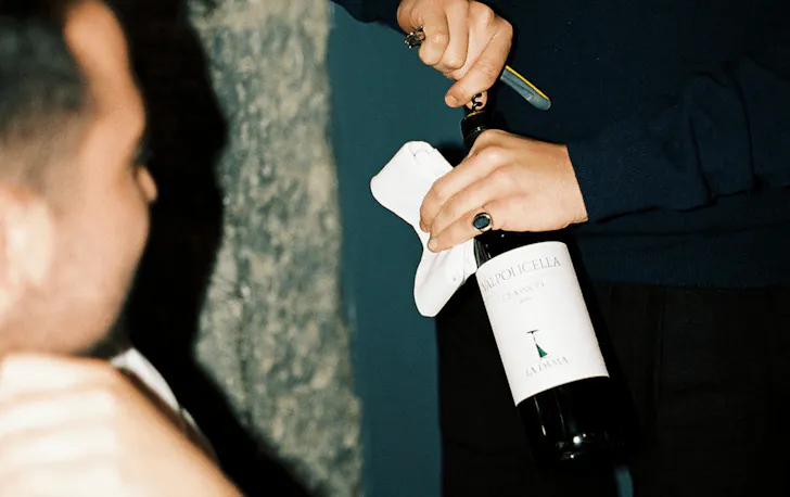 A person uncorking a bottle of wine. 