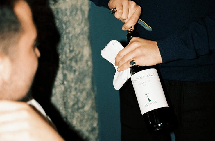 A person uncorking a bottle of wine. 