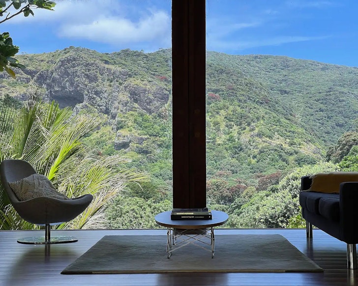 Floor to ceiling windows look out onto lush greenery, one of the best airbnbs with fireplaces in New Zealand.