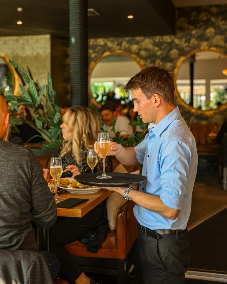 A waiter delivers drinks to a table at Aikmans. 