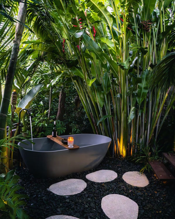 A view of the outdoor bathtub surrounded by greenery at Airlie Bungalows B3 one of the best Airlie Beach Airbnbs