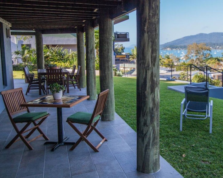 Chairs of the deck and grass overlooking the view at Airlie Guest House one of the best Airlie Beach Airbnbs 