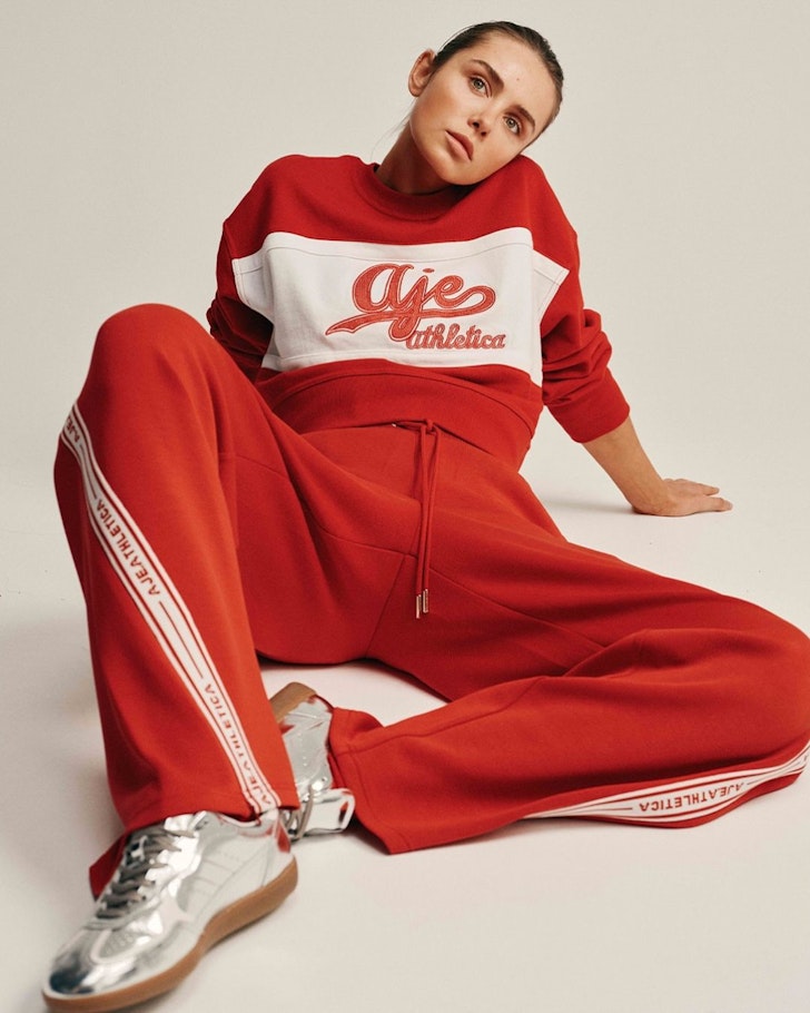 A woman wears matching red sweatpants and top from Aje Athletica one of the best activewear brands