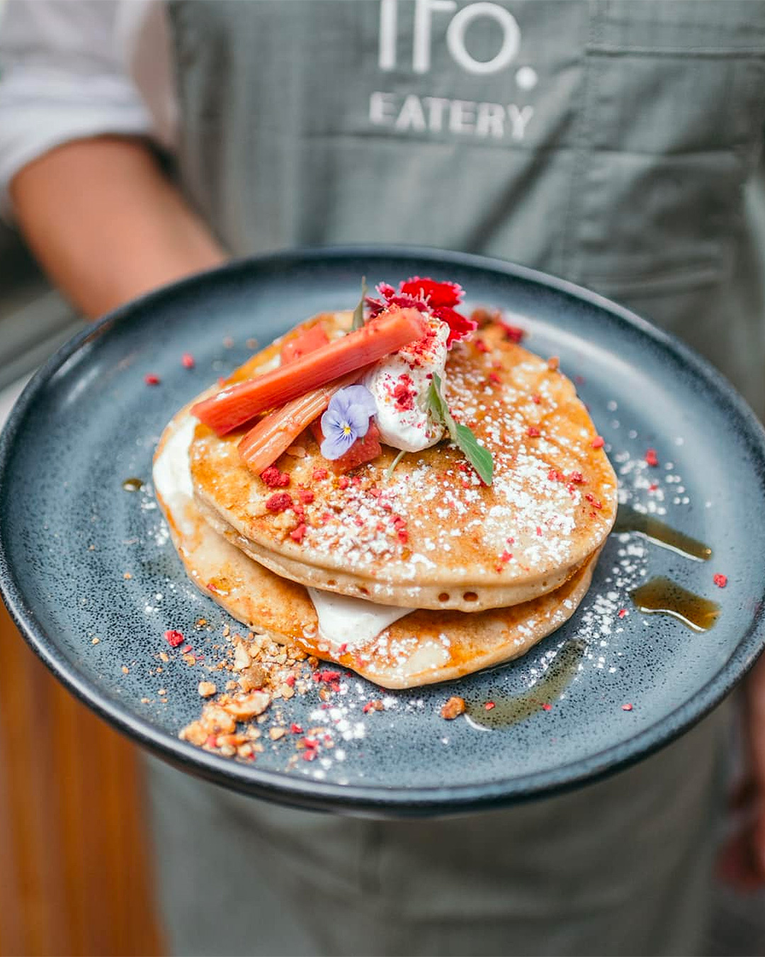 Someone holds a plate of fluffy pancakes at Akito Eatery in Waiheke.