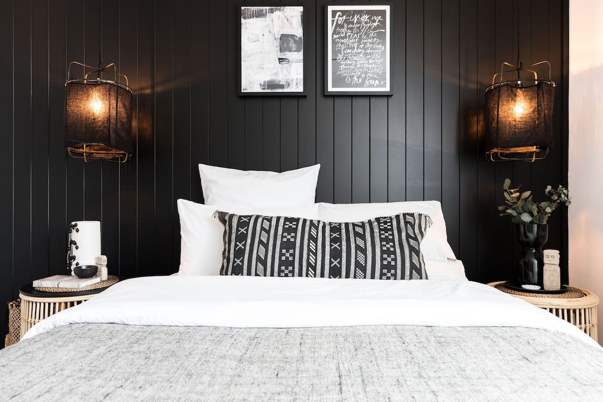 a bed with boho furnishings in front of a black wall