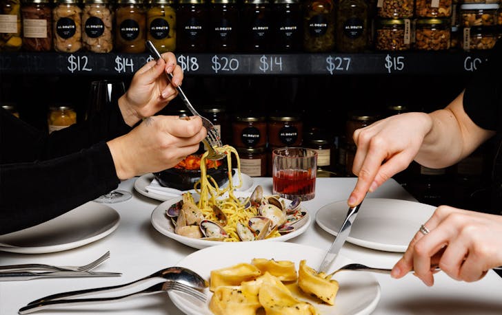 Two people digging into plates of pasta at one of the best Italian restaurants in Melbourne