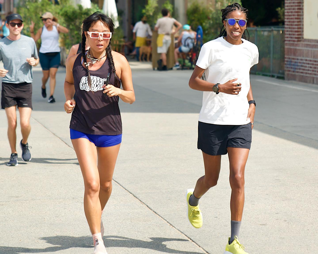 Two people clad in Allbirds shoes and activewear running along a sidewalk. 