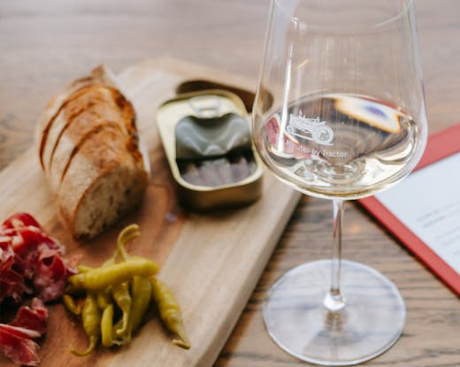 A table with a glass of white wine and charcuterie. 