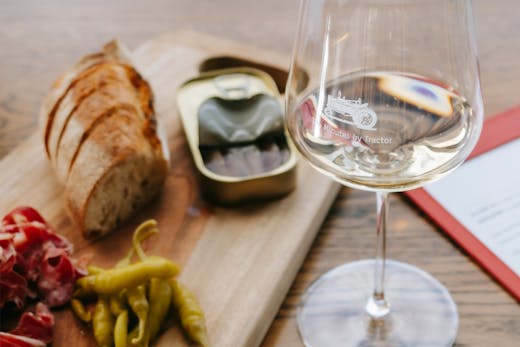 A table with a glass of white wine and charcuterie.