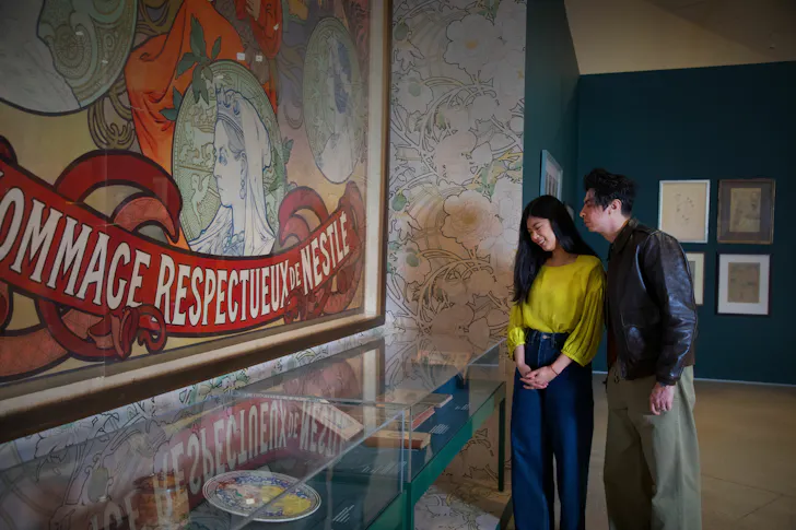 Two people looking at art on wall.