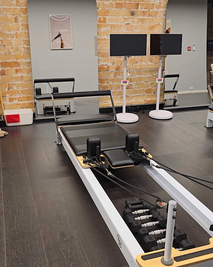 A cute one-person reformer pilates set up in a brick-lined studio. 