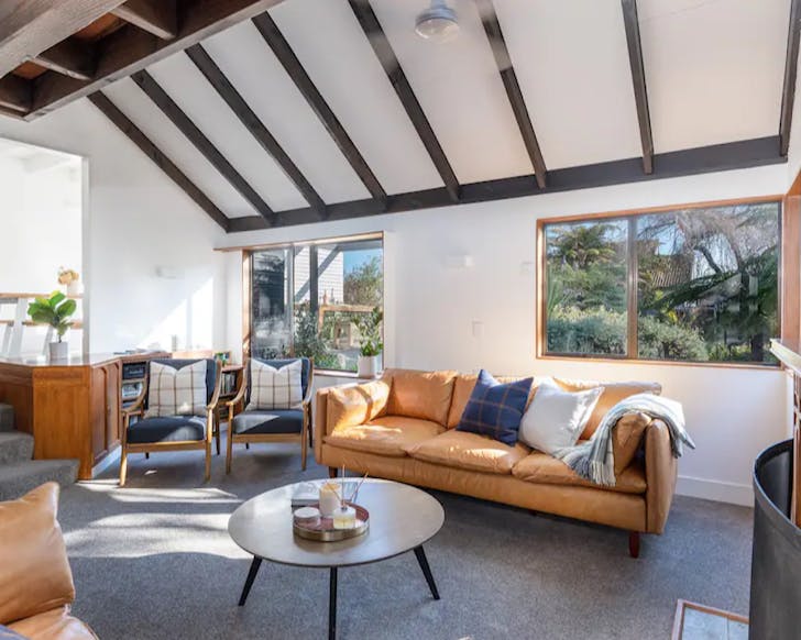 A cosy-looking lounge with a yellow couch in one of Taupoâs best airbnbs. 