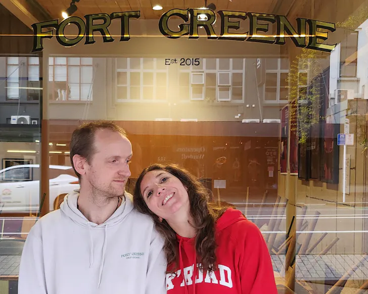 Andrea and Liam sit together up against the outside of Fort Greene after hours. 