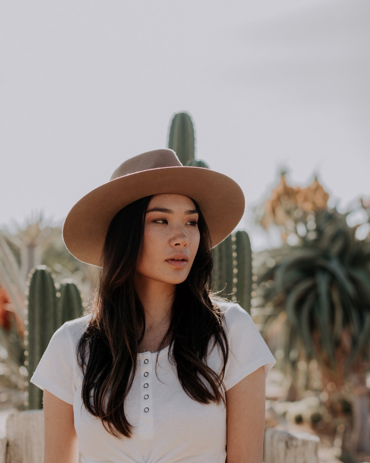 A woman stands in the desert wearing a wool hat.