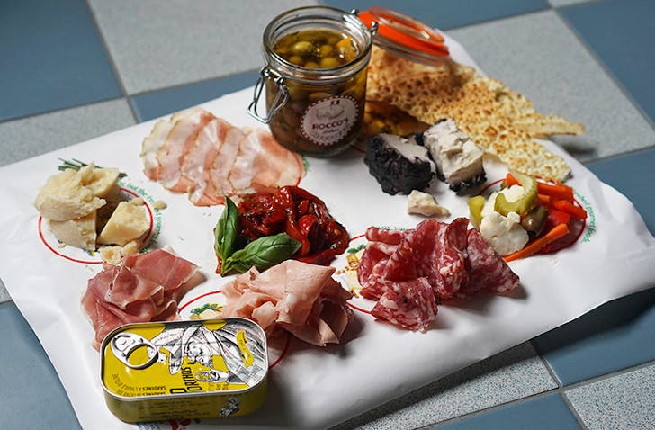 Rocco's antipasti platter stacked with cured meats, olives, cheeses and crips.