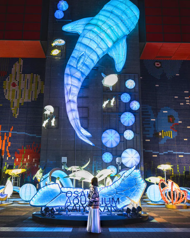 A neon-lit whale light installation at the entrance of Osaka Aquarium Kaiyukan. 