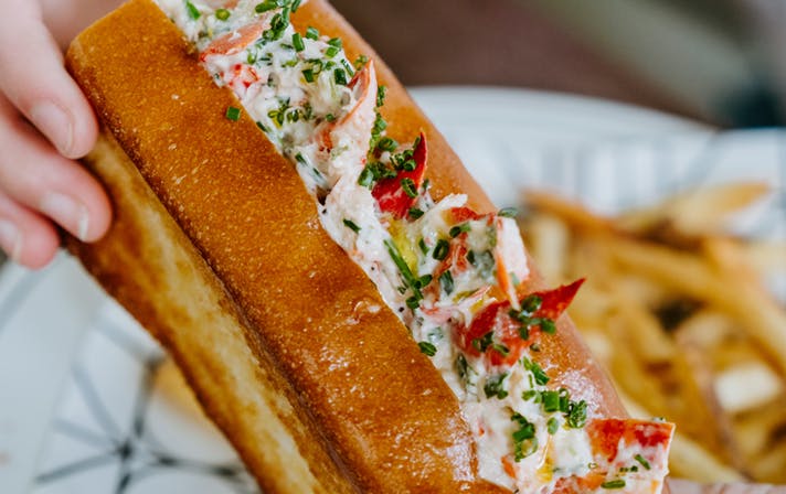 A person holding one of the best lobster rolls Melbourne has. 
