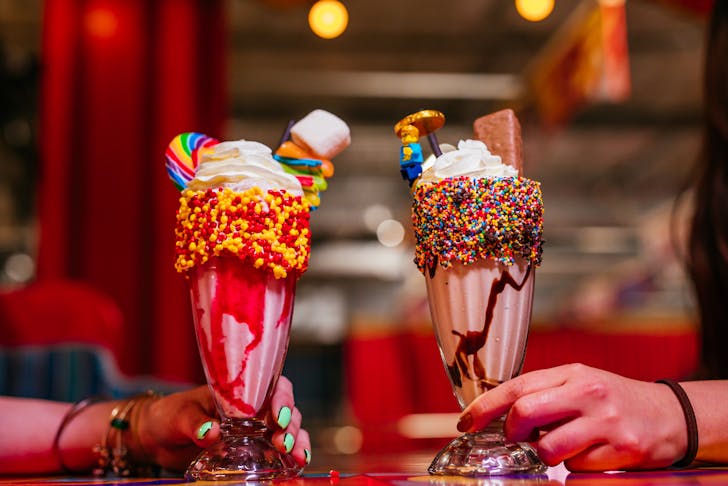 A strawberry and chocolate shake complete with sprinkles, cream and candy on top.