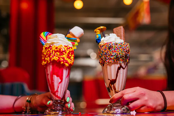 A strawberry and chocolate shake complete with sprinkles, cream and candy on top.