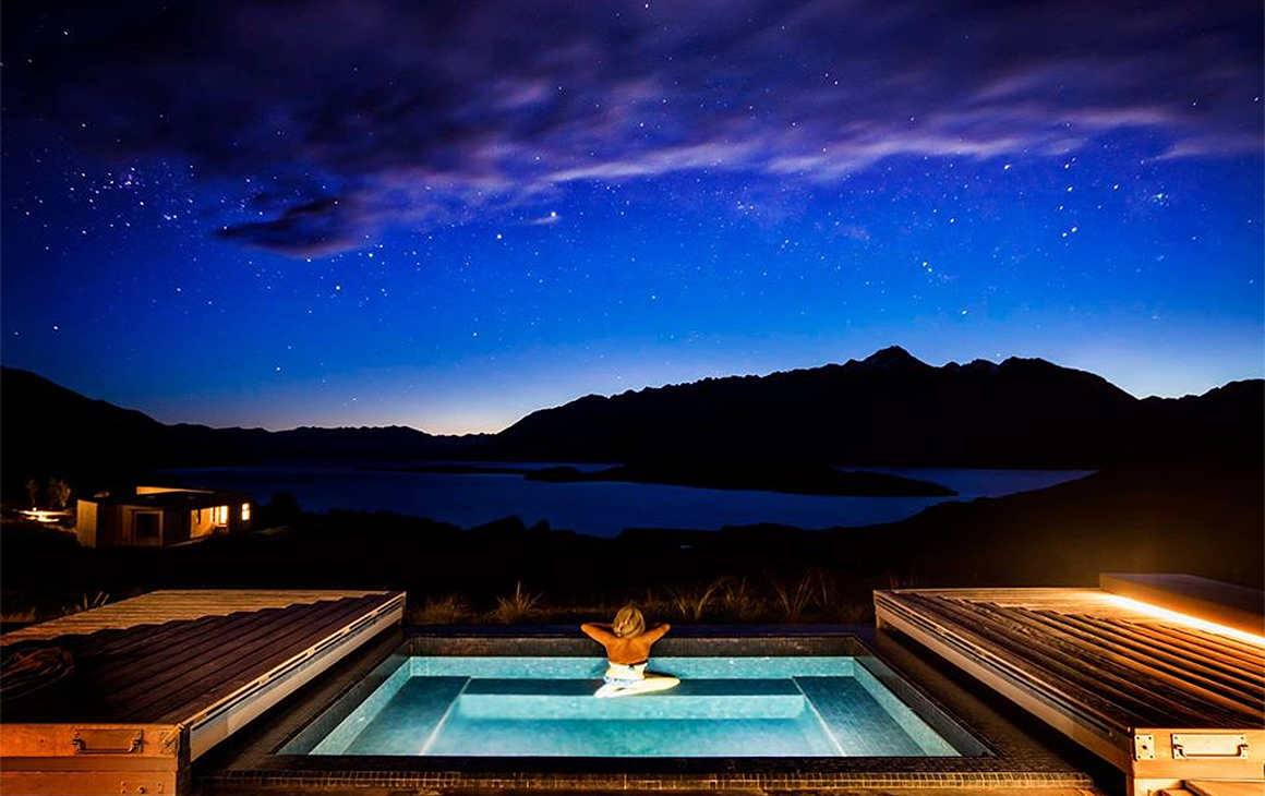 A woman relaxes in a spa under the stars at Aro Ha retreat.