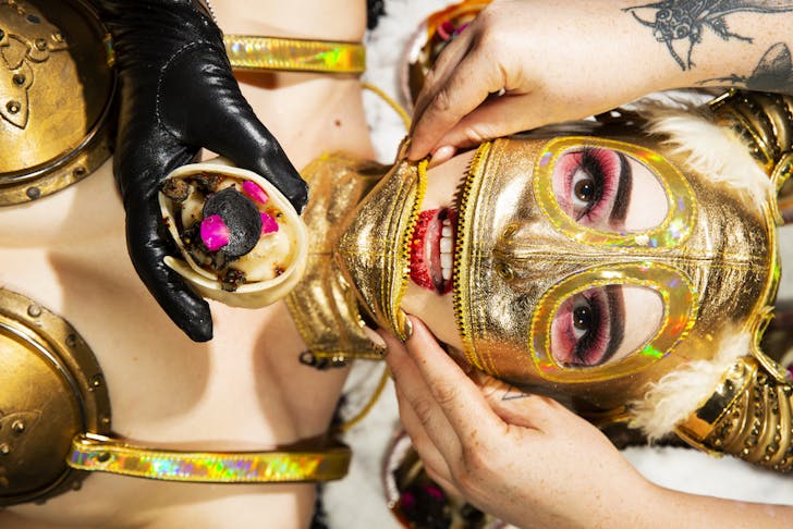 Model in gold mask being fed as part of Art Feast