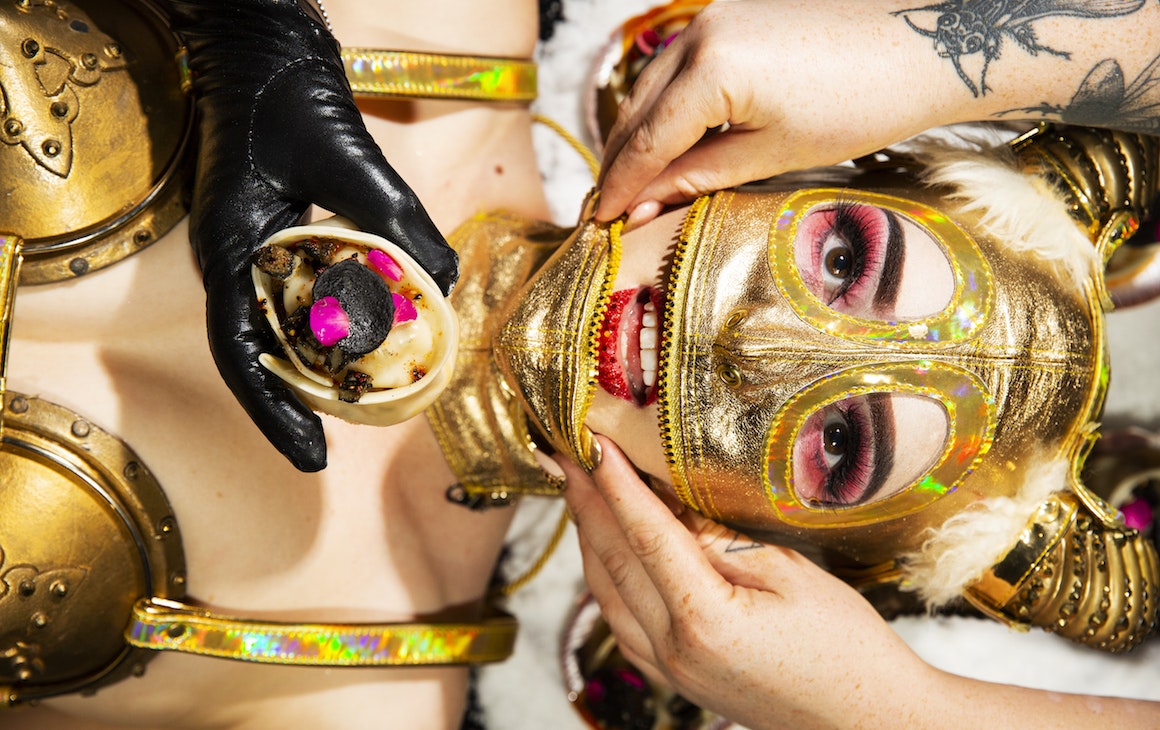 Model in gold mask being fed as part of Art Feast