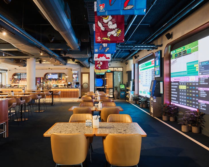 A large bar in the background with sports flags hanging above and a massive screen showing sports games to the right hand side