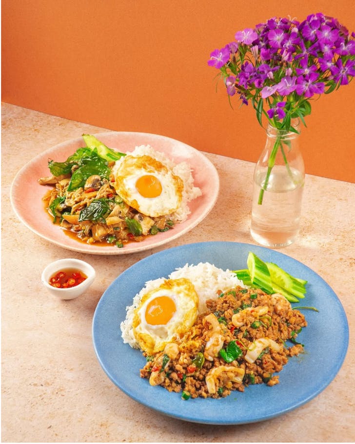 two thai dishes topped with fried eggs at boon cafe in haymarket in sydney