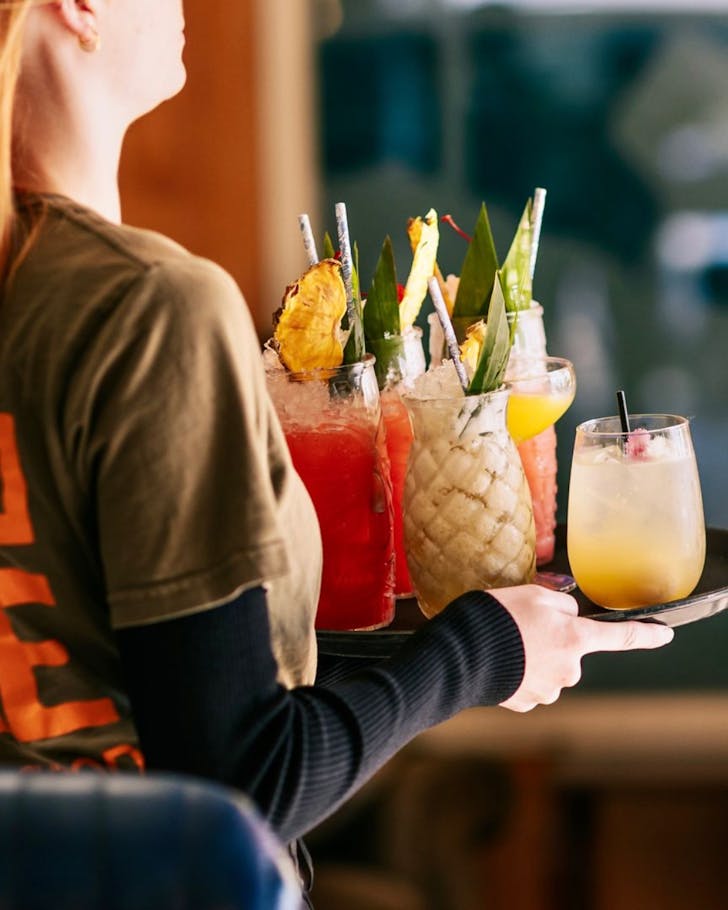 A member of Astrolabe's staff carries a tray of colourful cocktails.