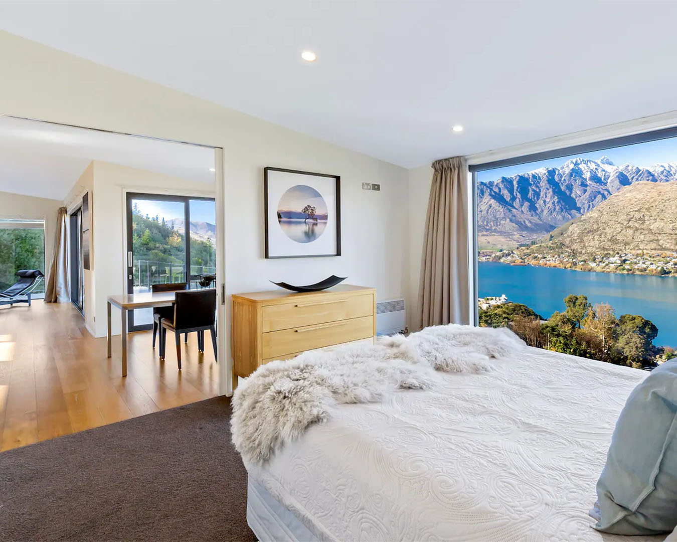 A cosy bedroom and living area looks out over lake Wakatipu, one of the best airbnbs with fireplaces in New Zealand.