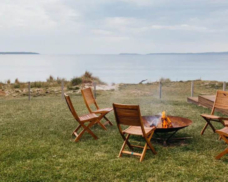 Deck chairs around a fire pit overlooking the ocean at Atra, Callala Beach