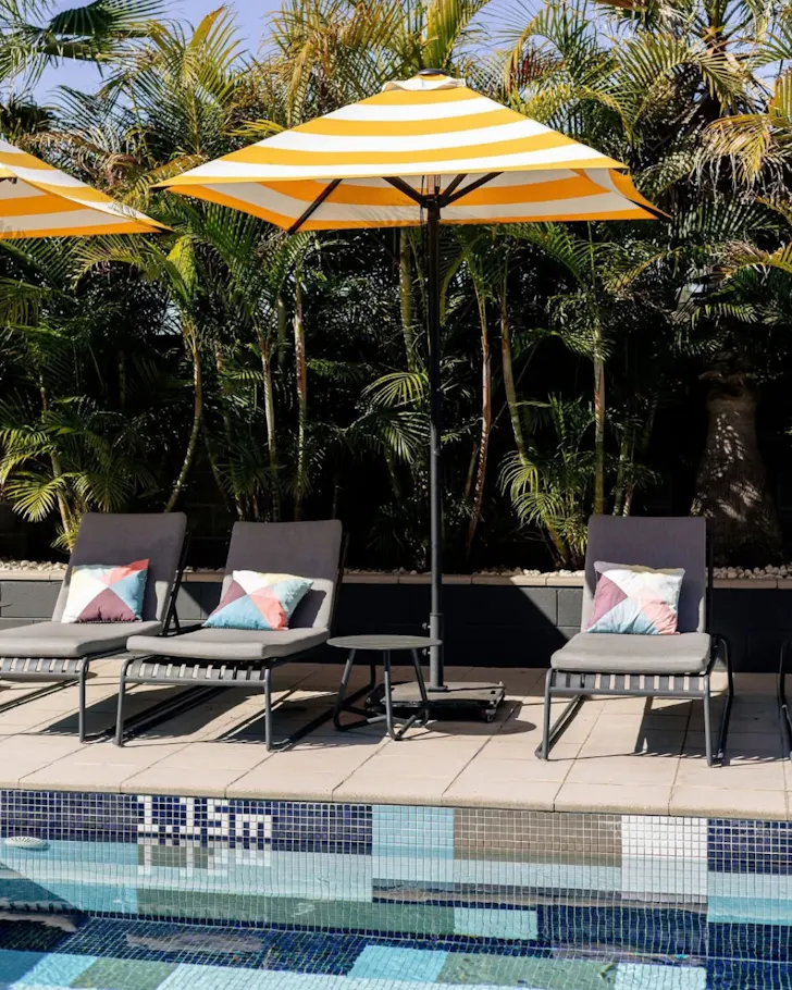 Sun loungers and a yellow umbrella by the pool at Atura Blacktown.