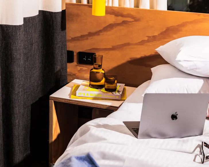 A hotel bed with a laptop on the pillows at Atura Oran Park.