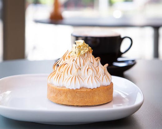 A lemon meringue pie sits atop a white plate