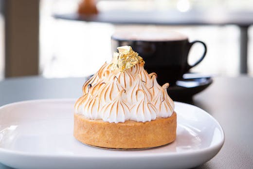 A lemon meringue pie sits atop a white plate