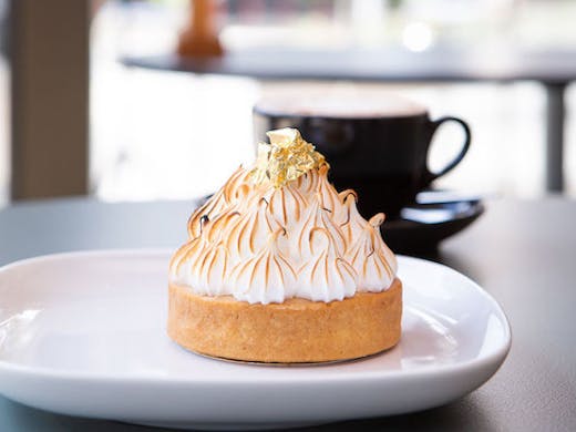 A lemon meringue pie sits atop a white plate