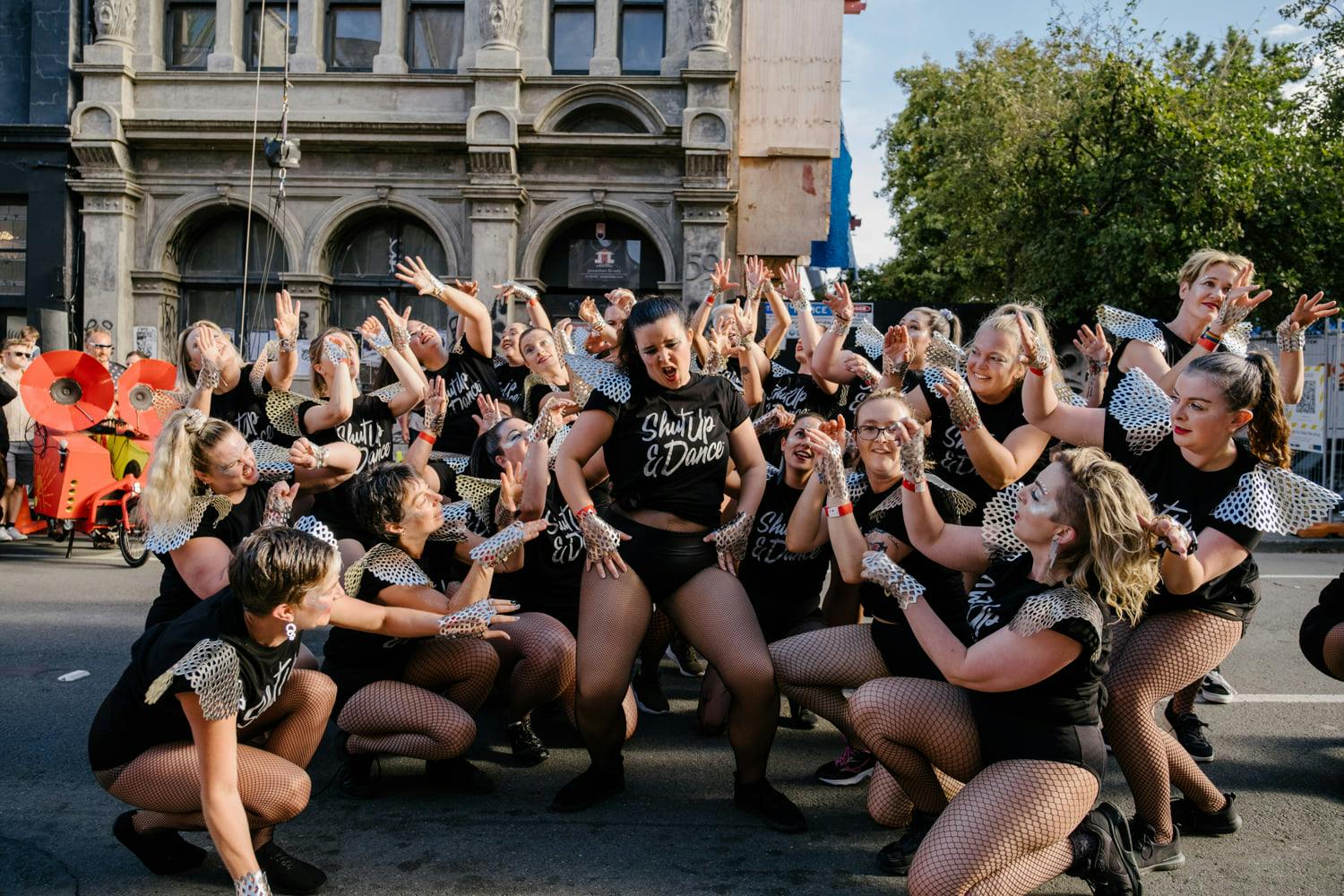 A group of people dancing gather around one posing sassily. 