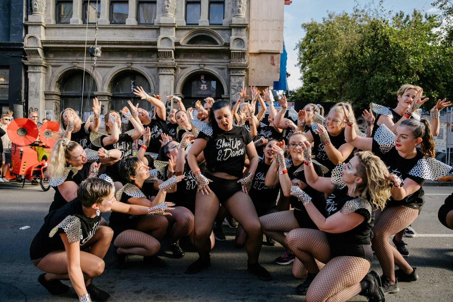 A group of people dancing gather around one posing sassily. 