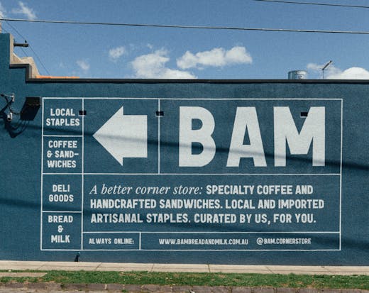The side of a wall with a large white-sign painted onto that reads 'BAM'.