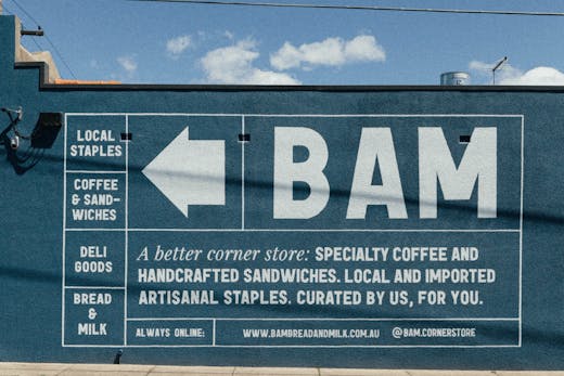 The side of a wall with a large white-sign painted onto that reads 'BAM'.