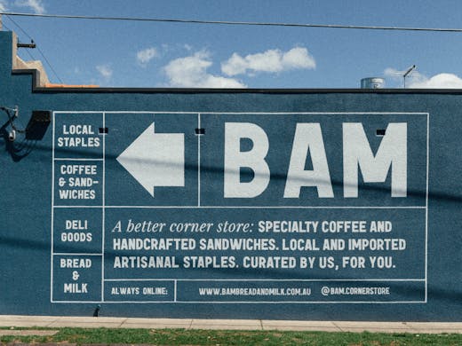 The side of a wall with a large white-sign painted onto that reads 'BAM'.
