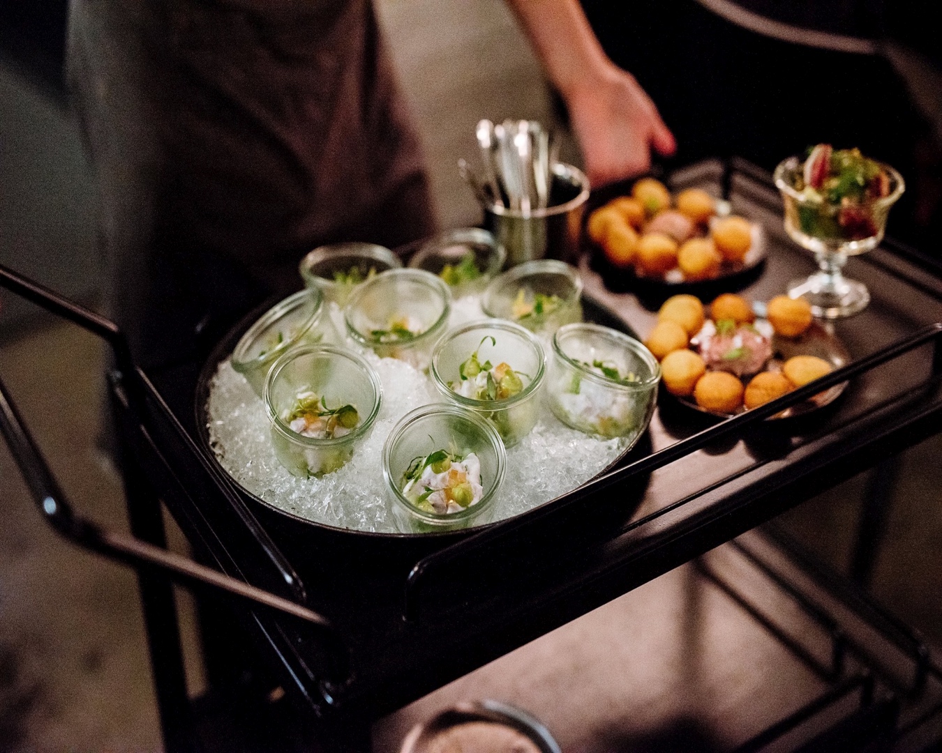 Delectable looking nibbles in glass jars on ice and platters of parfait doughnuts on a trolley