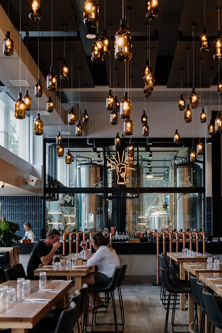 the interior of a brewpub with bottles hanging from the ceiling as lights
