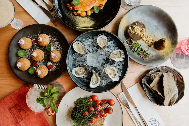 a table atop which sit several dishes including oysters, profiteroles and other