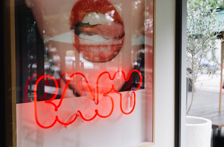 A red neon sign that reads 'Baby' in a storefront window. 
