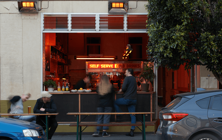 An open shopfront window looking into one of the best bars in Melbourne with orange lighting. 