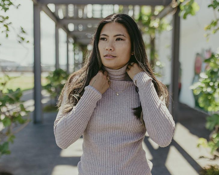 A woman wears a sheer, ribbed turtleneck skivvy by Standard Issue and walks through Silo Park. 