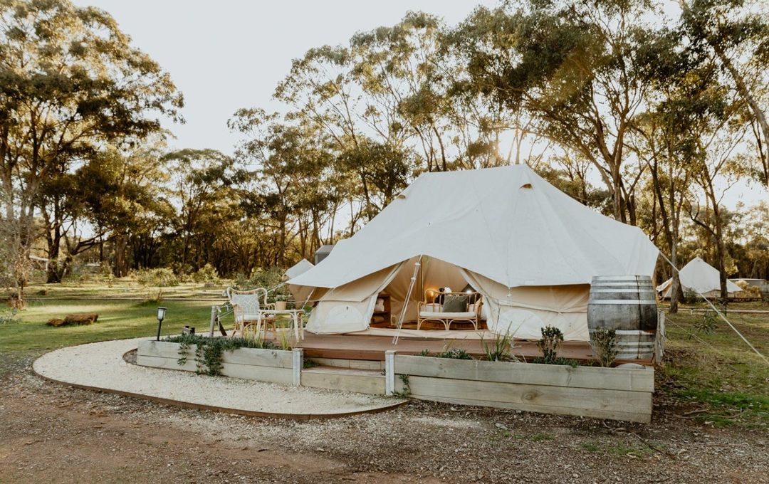 A cream coloured glamping tent on a platform surrounded by bush, a glamping victoria option.