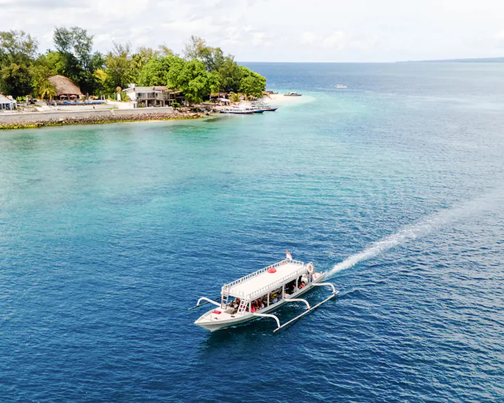 A boat glides along the pristine blue waters of Bali.