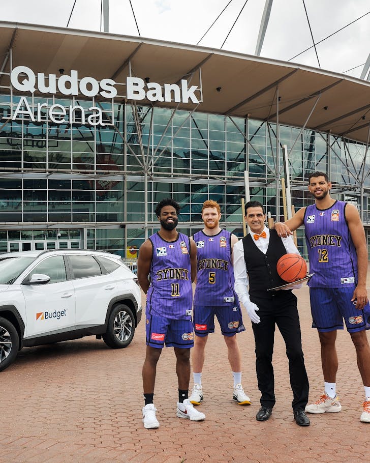 Sydney Kings players standing with a butler outside Qudos Bank Arena